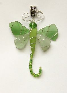 a green glass and metal keychain with a dragon on it's back