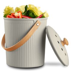 a white bucket filled with vegetables and a wooden handle