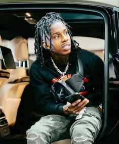 a man with dreadlocks sitting in the back seat of a car