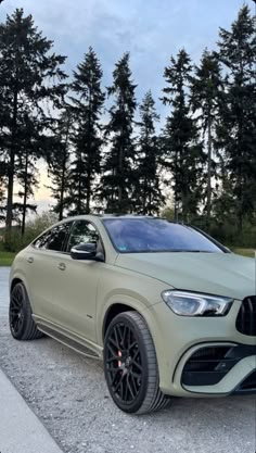 a beige car parked in front of some trees