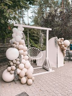 some balloons are hanging on the side of a white structure with chairs and tables in the background