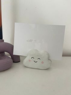 there is a small white cloud next to a purple object on the table with a card in it