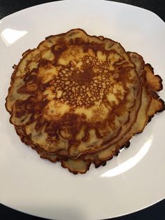 three pancakes on a white plate sitting on a table