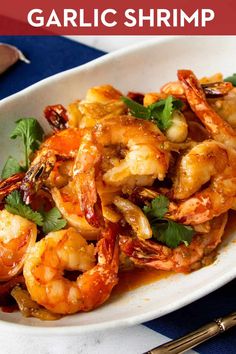 a white plate topped with cooked shrimp and garnished with cilantro