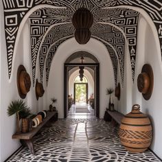 a hallway with black and white designs on the walls, potted plants and benches