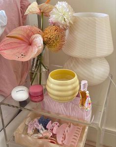 a vase with flowers and other items sitting on a glass shelf next to a bed