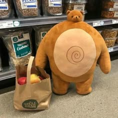 a stuffed bear is next to a bag of nuts and an apple in a grocery store