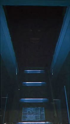 an empty hallway with blue light coming from the ceiling and stairs leading up to it