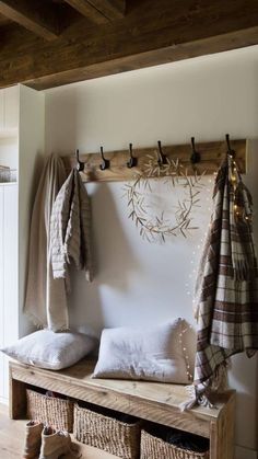 a wooden bench sitting in front of a coat rack filled with blankets and pillows on top of it