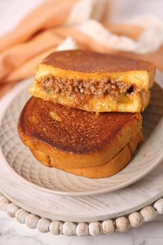 two grilled sandwiches sitting on top of a white plate next to some bread sticks