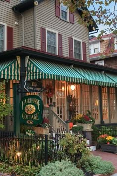 the front of a building with green and white awnings on it's windows