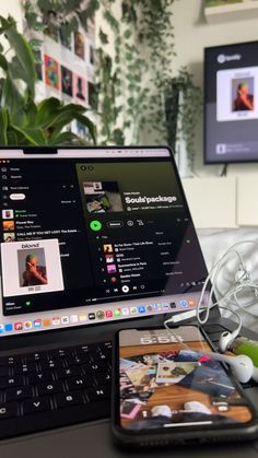 an open laptop computer sitting on top of a desk next to a cell phone and headphones