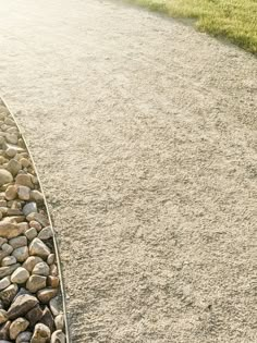 a bench sitting on the side of a road next to a pile of rocks and grass