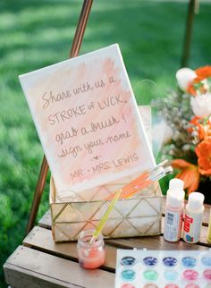 a sign that is sitting on top of a wooden table with some paint and markers