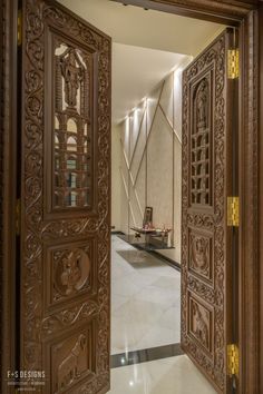 an open wooden door with intricate carvings on the doors and floor in front of it