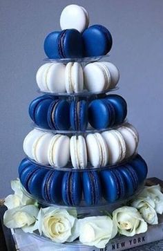 there is a blue and white cake with macaroons on the top, surrounded by flowers