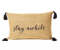 a pillow with the words stay awhile on it and tasselled black fringes