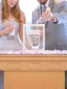 a man and woman standing next to each other in front of a table with pictures on it