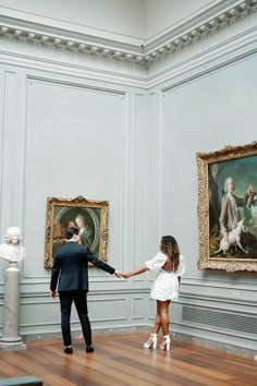 a man and woman holding hands in an art gallery