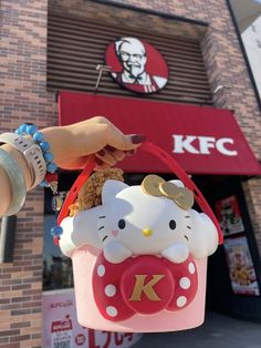 a person holding a hello kitty bag in front of a kfc