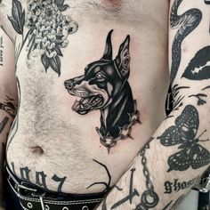 a man with tattoos on his chest has a doberman tattoo on his left side