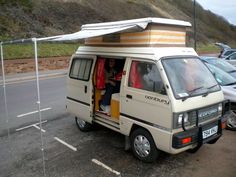 an old camper van parked in a parking lot with its doors open and people inside