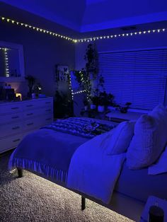 a bedroom with blue lights on the ceiling and bed in the foreground is a white dresser