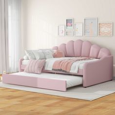 a pink daybed in a white room with pictures on the wall and flooring