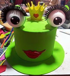 a green cake with two eyes and a crown on top