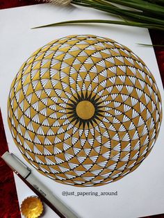 a paper with an intricate design on it next to a pen and some other items