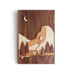 a wooden wall hanging with mountains and trees