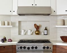 a stove top oven sitting inside of a kitchen next to white cabinets and counter tops