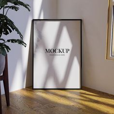 a mock up poster next to a potted plant on a wooden floor in front of a white wall