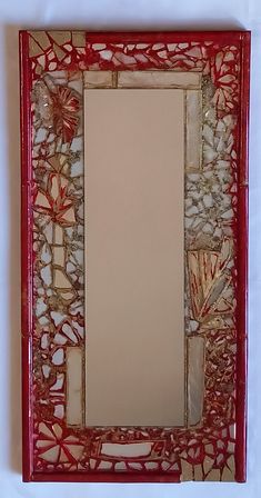 a red frame with flowers and shells in it on a white tableclothed surface