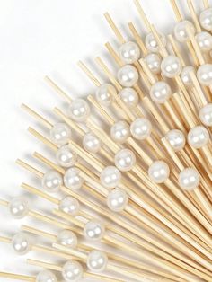 a bunch of wooden sticks with some white pearls on top of each one in front of a white background