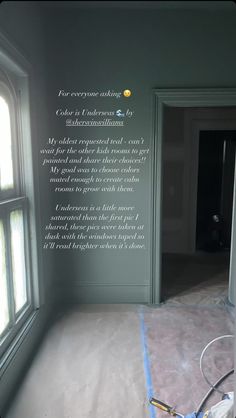 an empty room is being painted green with white lettering on the wall and windows in the background