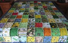 a quilted table cloth with many different colors and designs on it, sitting on top of a bed