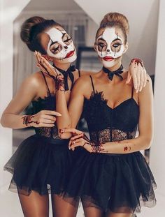 two women with face paint on their faces posing for a photo in front of a mirror