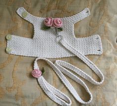 a crocheted baby outfit with flowers on it and two matching hair clips laying next to each other