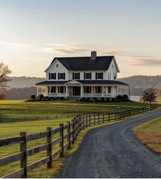 a large white house sitting on top of a lush green field next to a dirt road