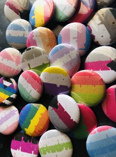 a pile of colorful buttons sitting on top of a black table next to each other