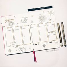 an open planner with fireworks on it next to a pen and two crayons