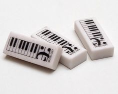 three small white keys with black and white piano symbols on them, sitting next to each other