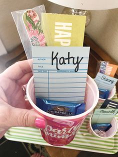 a person holding up a cup filled with candy and notes on top of each other