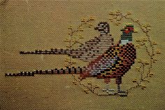 a close up of a cross stitch pattern with a bird on it's side