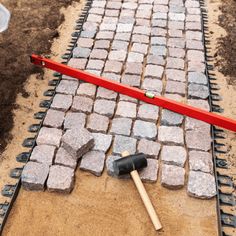 a brick walkway being built with tools laying on it