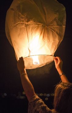 a person holding a lit up lantern in the dark