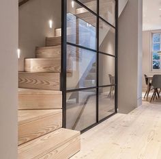 the interior of a modern home with wood floors and glass doors that lead to an upstairs dining area