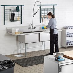 a woman is washing dishes in the kitchen sink while she stands at the faucet