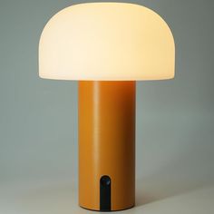 an orange table lamp with a white light on the top and black trim around it